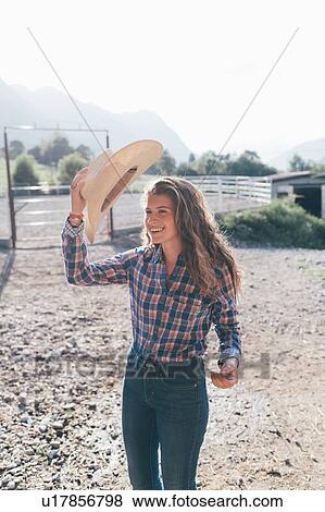 Cowgirl putting on stetson in rural equestrian arena View Large Photo Image Stock Photo - Cowgirl putting on stetson in rural equestrian arena. Fotosearch