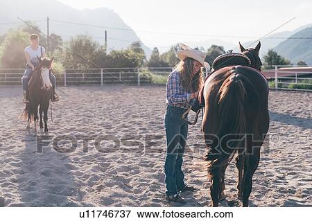 Cowgirl saddling horse in rural equestrian arena, Primaluna, Trentino-Alto Adige, Italy View Large Photo Image Stock Photo - Cowgirl saddling horse in rural equestrian arena, Primaluna, Trentino-Alto Adige, Italy. Fotosearch