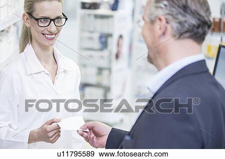 Stock Photo - Customer giving prescription to pharmacist in pharmacy.. Fotosearch