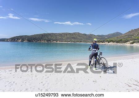 Stock Image - Cyclist on beach, Villasimius, Sardinia, Italy. Fotosearch
