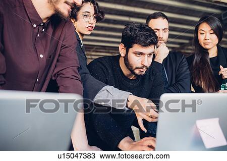 Stock Image - Designer showing presentation to colleagues in studio. Fotosearch