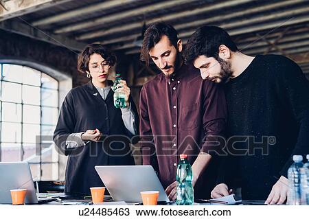 Stock Image - Designer showing presentation to colleagues in studio. Fotosearch