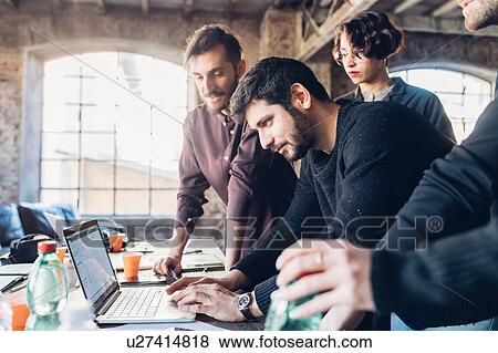 Stock Photo - Designer showing presentation to colleagues in studio. Fotosearch