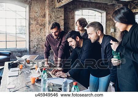 Stock Photograph - Designer showing presentation to colleagues in studio. Fotosearch