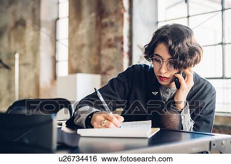 Stock Photograph - Designer talking on telephone at work. Fotosearch