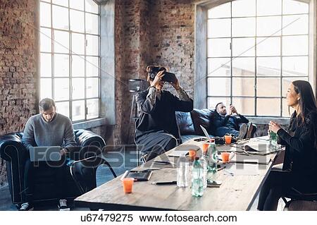 Designers testing virtual reality headset in communal space in studio View Large Photo Image Stock Photography - Designers testing virtual reality headset in communal space in studio. Fotosearch
