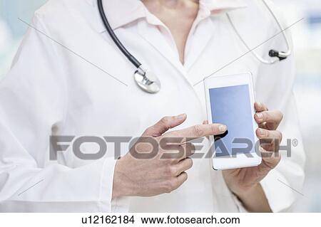 Picture - Doctor pointing at mobile phone screen.. Fotosearch