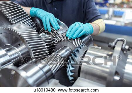 Stock Image - Engineer assembling gearbox in gearbox factory. Fotosearch