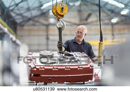 Stock Photo - Engineer assembling gearbox in gearbox factory. Fotosearch