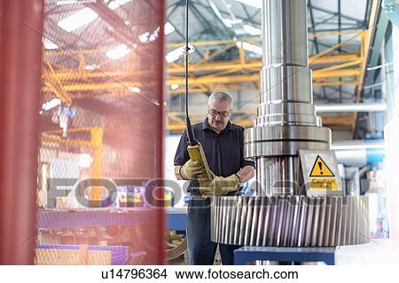 Engineer fitting spindle into heated gear wheel in gearbox factory View Large Photo Image Picture - Engineer fitting spindle into heated gear wheel in gearbox factory. Fotosearch