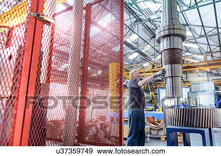 Engineer fitting spindle into heated gear wheel in gearbox factory View Large Photo Image Stock Photo - Engineer fitting spindle into heated gear wheel in gearbox factory. Fotosearch