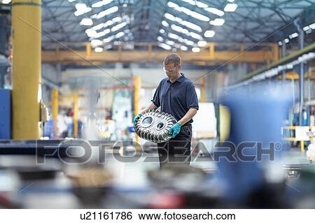 Stock Photograph - Engineer holding gearbox housing in gearbox factory. Fotosearch