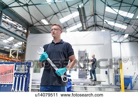 Engineer holding large spanner in gearbox factory View Large Photo Image Stock Image - Engineer holding large spanner in gearbox factory. Fotosearch