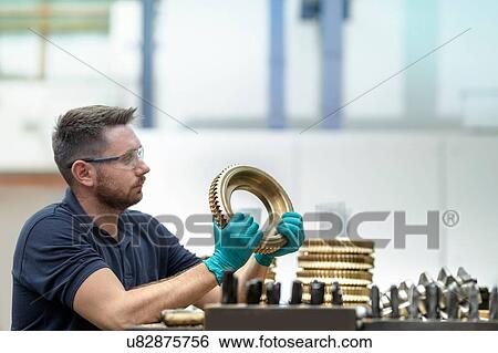 Stock Photograph - Engineer inspecting bronze parts in gearbox factory. Fotosearch