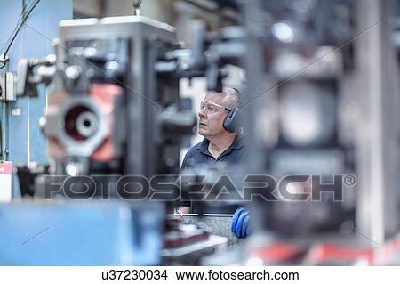 Engineer operating machine in gearbox factory View Large Photo Image Picture - Engineer operating machine in gearbox factory. Fotosearch
