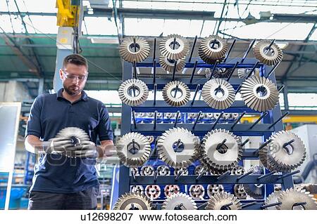 Stock Photo - Engineer selecting cutting tool in gearbox factory. Fotosearch