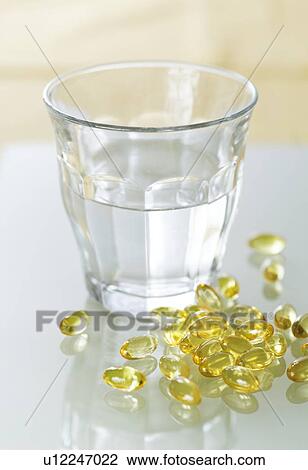 Evening primrose oil capsules in a pile next to a glass of water. View Large Photo Image Stock Image - Evening primrose oil capsules in a pile next to a glass of water.. Fotosearch