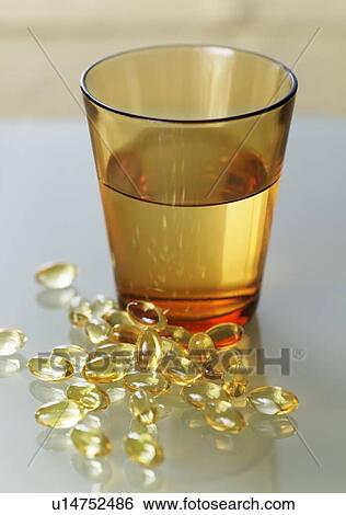 Evening primrose oil capsules in a pile next to a glass of water. View Large Photo Image Stock Photograph - Evening primrose oil capsules in a pile next to a glass of water.. Fotosearch