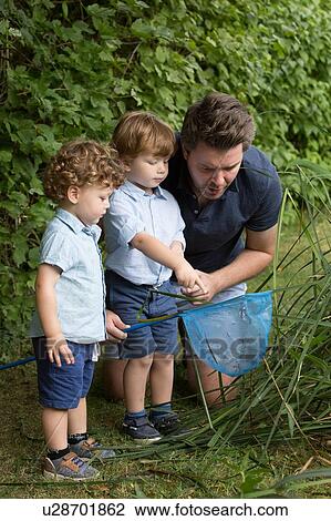 Stock Image - Father and children looking in fishing net. Fotosearch