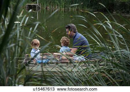 Stock Image - Father and children on boat ride in lake. Fotosearch