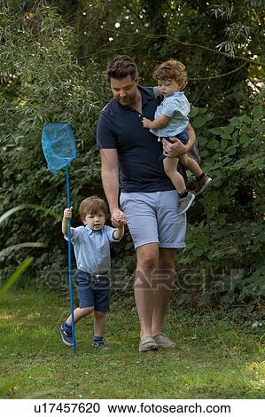 Stock Image - Father and children with fishing net in park. Fotosearch
