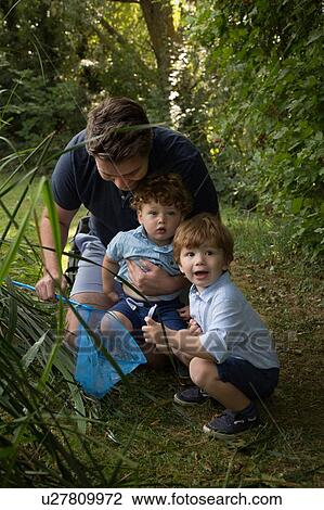 Stock Image - Father and children with fishing net in park. Fotosearch