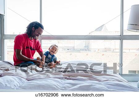 Father and son playing on bed View Large Photo Image Stock Photograph - Father and son playing on bed. Fotosearch