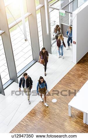 Stock Image - Female and male university students arriving by university lobby entrance. Fotosearch