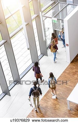 Stock Photo - Female and male university students leaving by university lobby entrance. Fotosearch