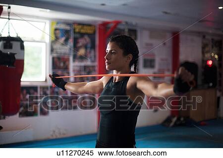 Stock Photography - Female boxer doing stretching exercise in gym. Fotosearch