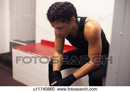 Stock Image - Female boxer resting in gym. Fotosearch