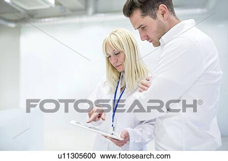 Stock Image - Female doctor discussing medical notes on digital tablet with consultant.. Fotosearch