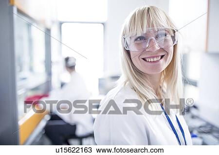Stock Image - Female doctor wearing protective goggles and smiling.. Fotosearch