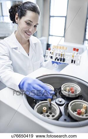 Stock Photo - Female laboratory assistant using centrifuge machine.. Fotosearch