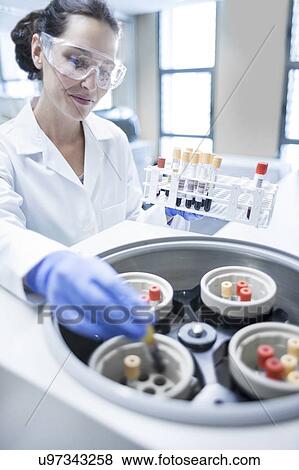 Stock Photo - Female laboratory assistant using centrifuge machine.. Fotosearch