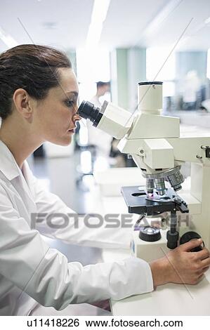 Stock Photograph - Female laboratory assistant using microscope.. Fotosearch