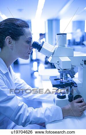 Stock Photograph - Female laboratory assistant using microscope.. Fotosearch