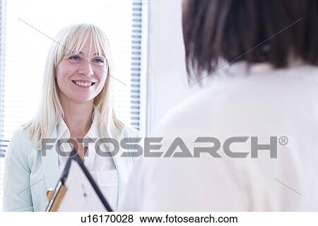 Stock Photo - Female patient listening to doctor and smiling.. Fotosearch