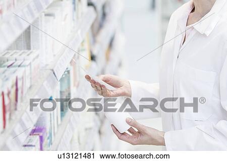 Female pharmacist reading prescription with pill bottle in one hand in pharmacy. View Large Photo Image Stock Image - Female pharmacist reading prescription with pill bottle in one hand in pharmacy.. Fotosearch