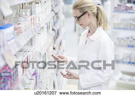 Female pharmacist reading prescription with pill bottle in one hand in pharmacy. View Large Photo Image Stock Photo - Female pharmacist reading prescription with pill bottle in one hand in pharmacy.. Fotosearch