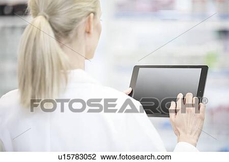 Stock Image - Female pharmacist using digital tablet in pharmacy.. Fotosearch