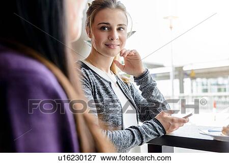 Stock Photo - Female student friends chatting by cafe window. Fotosearch