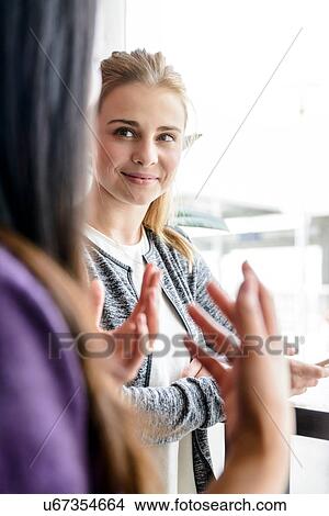 Picture - Female student friends chatting by university window. Fotosearch