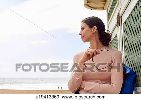Stock Photo - Female tourist looking over her shoulder at beach, Las Palmas, Gran Canaria, Canary Islands, Spain. Fotosearch