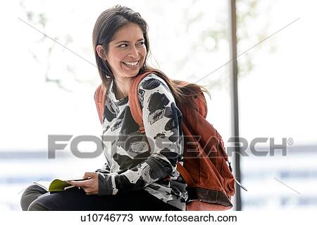 Female university student sitting on table in university lobby looking over her shoulder View Large Photo Image Stock Image - Female university student sitting on table in university lobby looking over her shoulder. Fotosearch