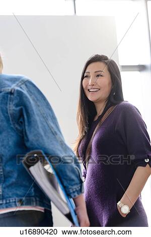 Stock Image - Female university students chatting together in university lobby. Fotosearch