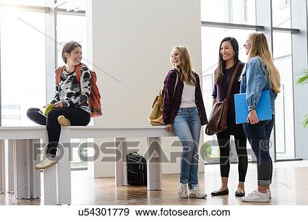 Stock Photo - Female university students chatting together in university lobby. Fotosearch