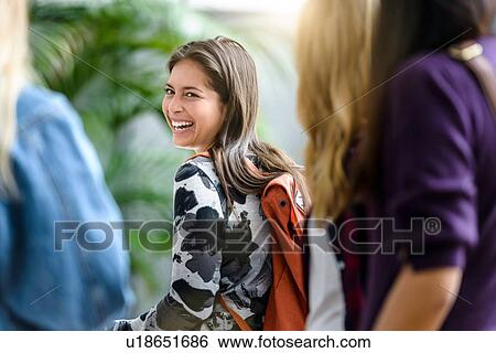 Stock Photograph - Female university students walking and talking in university lobby, cropped. Fotosearch