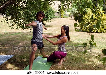 Female yoga teacher teaching young man yoga in garden, warrior pose View Large Photo Image Stock Photography - Female yoga teacher teaching young man yoga in garden, warrior pose. Fotosearch