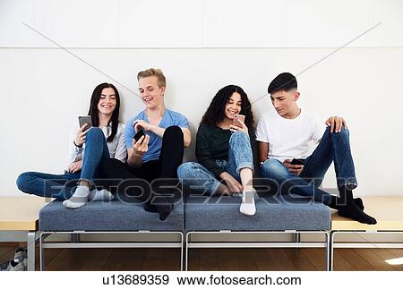 Four high school students on seating looking at smartphones View Large Photo Image Stock Photo - Four high school students on seating looking at smartphones. Fotosearch